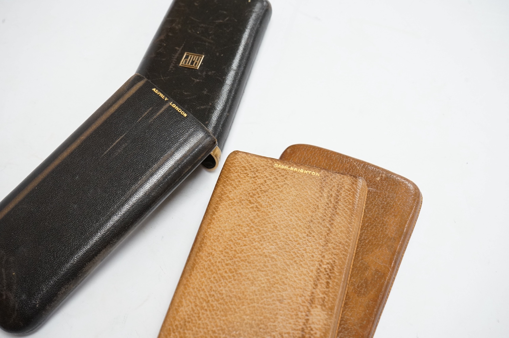 A George V 9ct gold mounted black leather cigar case, made and retailed by Asprey and Co, London, 1928, 17cm and one other yellow metal mounted leather cigar case, both with monogram appliqué and both belonged to Sir Joh